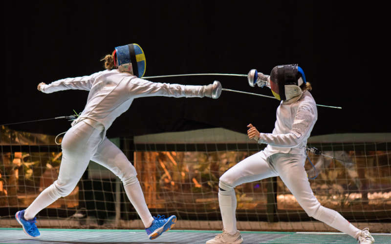 Two woman fencing athletes fight on professional sports arena