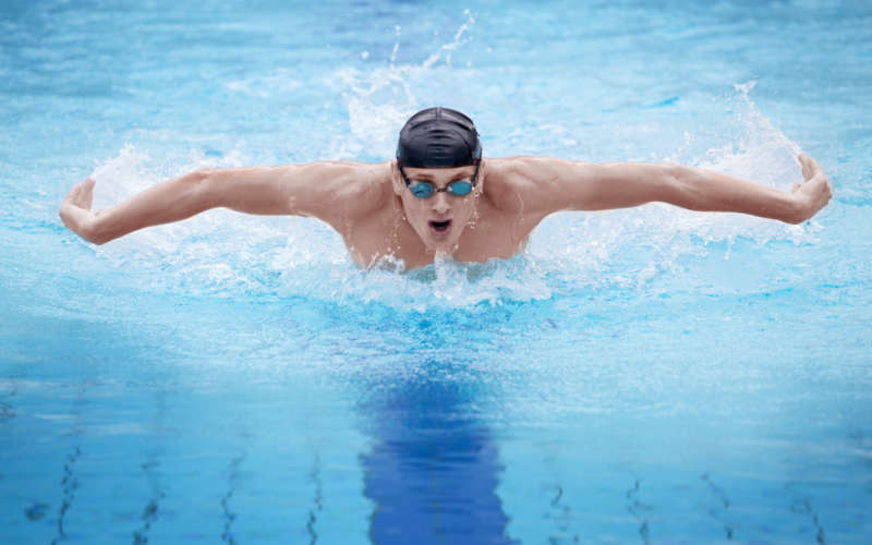 Swimmer in cap breathing performing the butterfly stroke